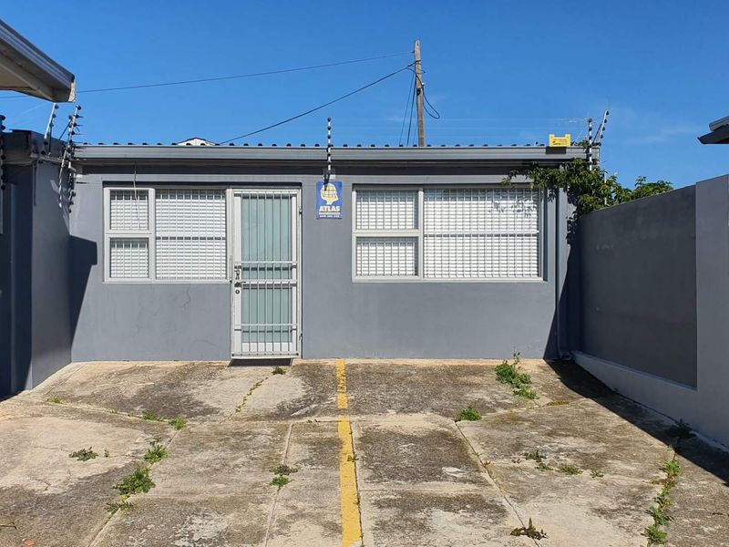Rear exterior view of the office building featuring a paved courtyard area, security gate, and perimeter electric fencing.