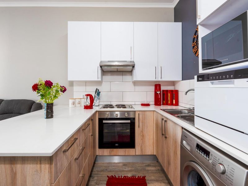 Modern kitchen featuring light wood cabinetry, white quartz countertops, subway tile backsplash, built-in oven, hob, extractor fan, and integrated microwave.