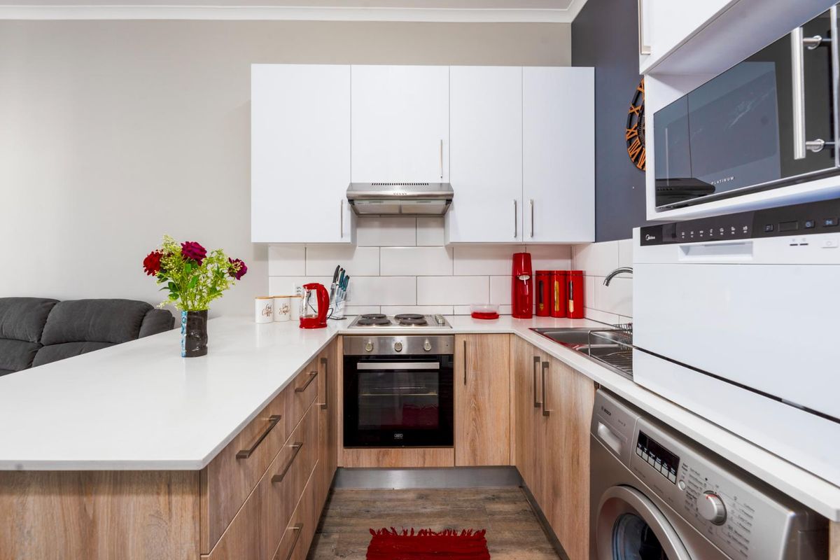 Modern kitchen featuring light wood cabinetry, white quartz countertops, subway tile backsplash, built-in oven, hob, extractor fan, and integrated microwave.