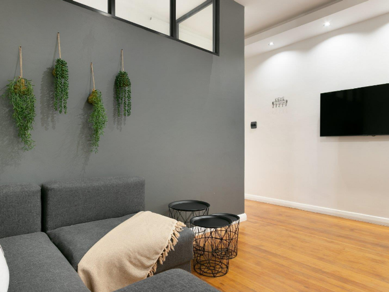 Modern living room featuring warm timber flooring, recessed downlighting, and a stylish internal glass partition wall.