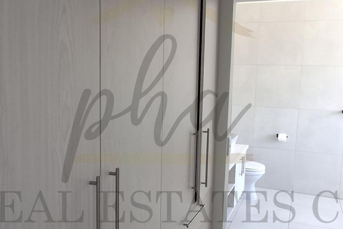A modern bathroom featuring built-in cabinetry, tiled walls and flooring, and a clean, minimalist layout.