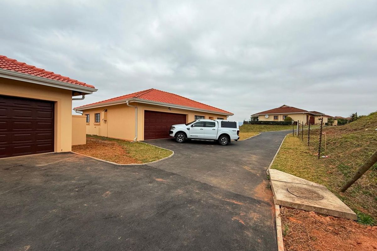 Exterior view of a townhouse complex featuring paved driveways, tiled roofs, and attached garages with brown sectional doors.