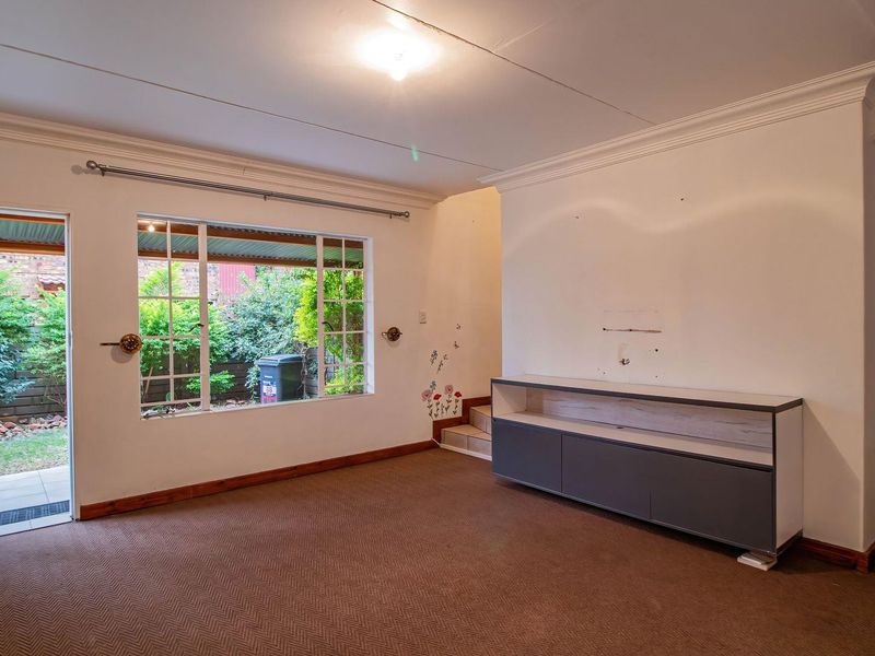 Spacious living area featuring crown molding, large windows providing natural light, and direct access to an outdoor patio area.
