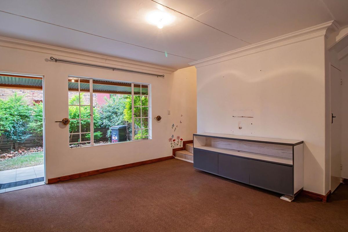 Spacious living area featuring crown molding, large windows providing natural light, and direct access to an outdoor patio area.