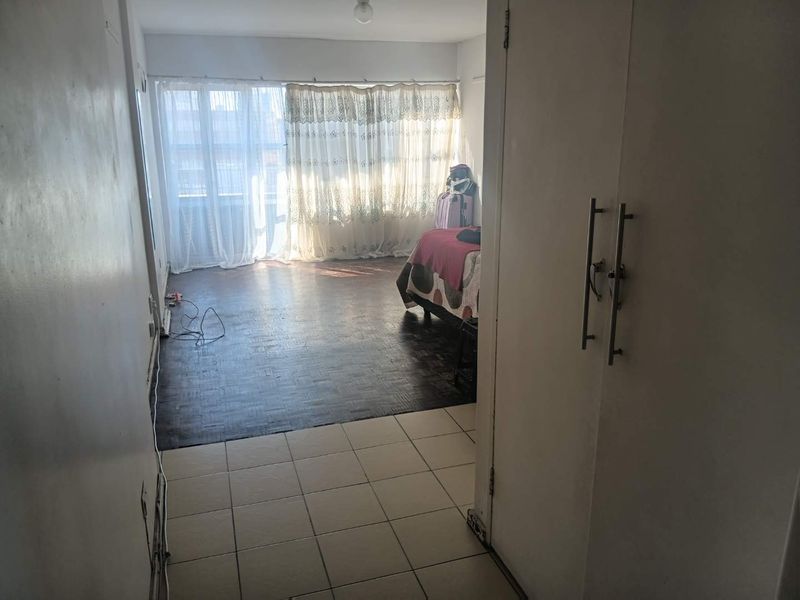 Bedroom featuring a combination of tiled and parquet flooring with a built-in cupboard, offering a functional space with potential for cosmetic updates.