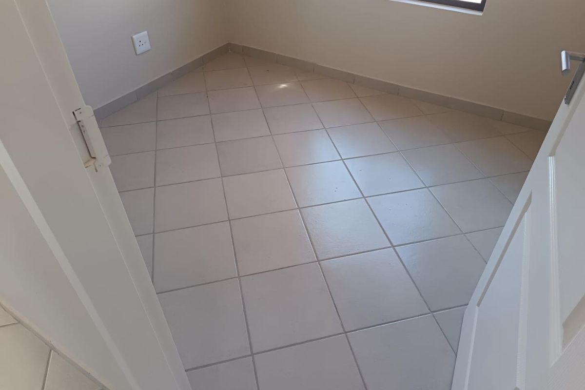 A clean, empty bedroom featuring neutral tiled flooring and a single window, providing a blank canvas for interior design.