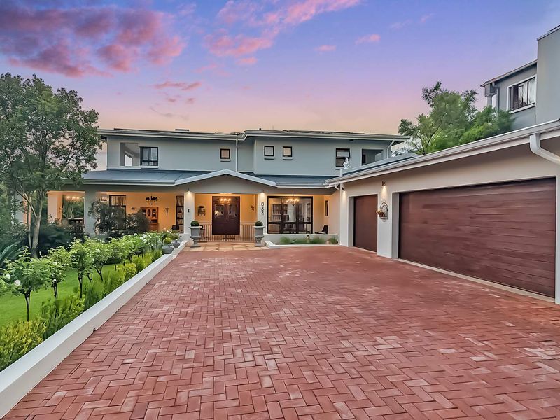 A well-maintained double-story residence featuring a spacious paved driveway, double garage, and an inviting covered entrance set within a landscaped garden.