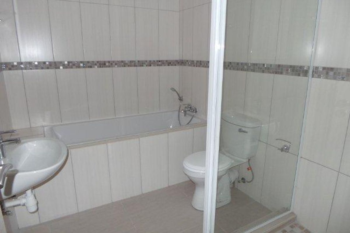 A functional bathroom featuring a built-in bathtub, a separate shower enclosure with glass door, a pedestal basin, and a toilet.