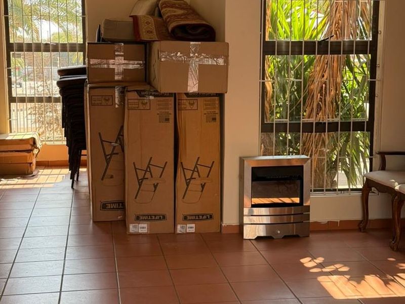 Living area featuring tiled flooring, large windows with security bars, and a built-in electric fireplace.
