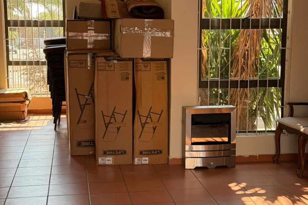 Living area featuring tiled flooring, large windows with security bars, and a built-in electric fireplace.