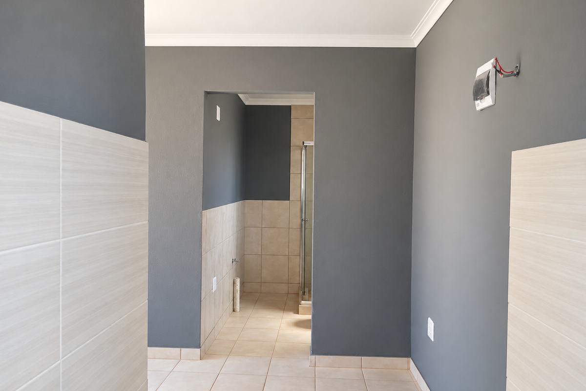 A clean, empty bathroom space featuring neutral wall and floor tiling, a shower enclosure, and modern grey painted walls.