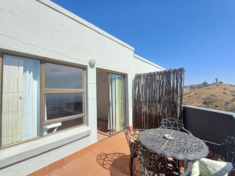 A private balcony featuring terracotta tiling, sliding door access to the interior, and elevated views of the surrounding landscape.