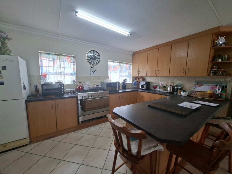 A functional kitchen featuring wooden cabinetry, laminate countertops, a gas stove, and a central island with tiled flooring throughout.