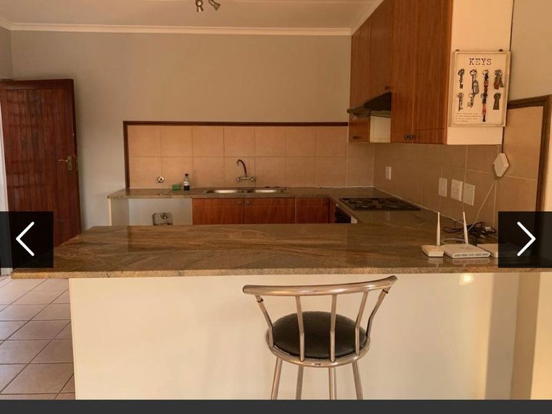 A functional kitchen featuring granite countertops, built-in cabinetry, a double basin sink, and a built-in hob with an extractor fan.