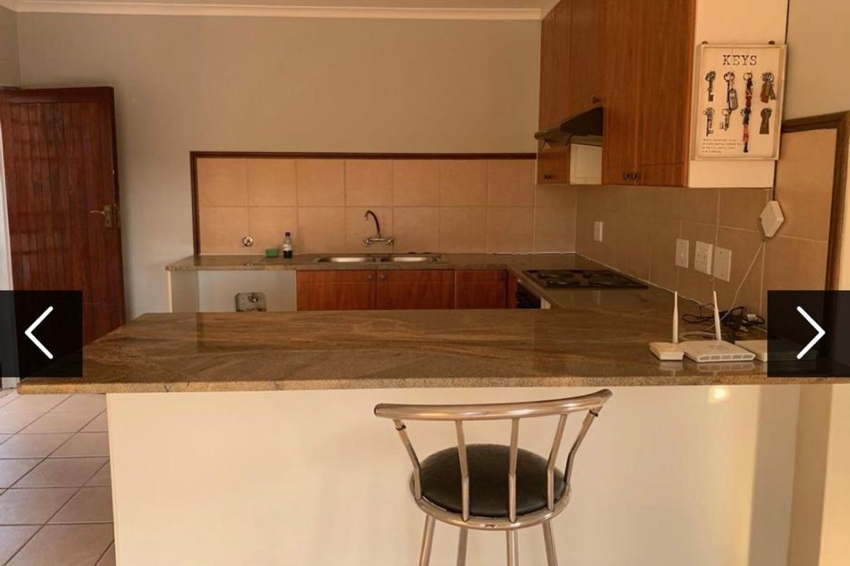 A functional kitchen featuring granite countertops, built-in cabinetry, a double basin sink, and a built-in hob with an extractor fan.