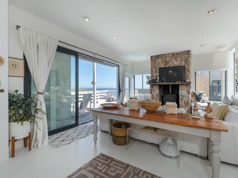Bright living room featuring a prominent stone fireplace with a wood-burning stove and large sliding glass doors opening to an outdoor deck.