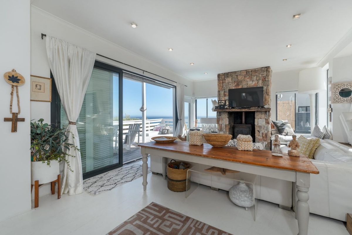 Bright living room featuring a prominent stone fireplace with a wood-burning stove and large sliding glass doors opening to an outdoor deck.