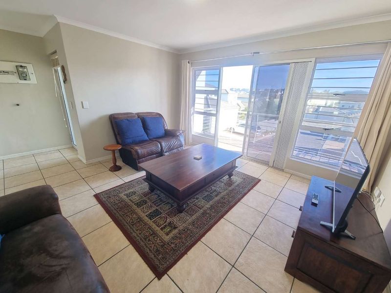 A living room featuring tiled flooring and large sliding glass doors that provide access to an outdoor area, offering natural light and ventilation.