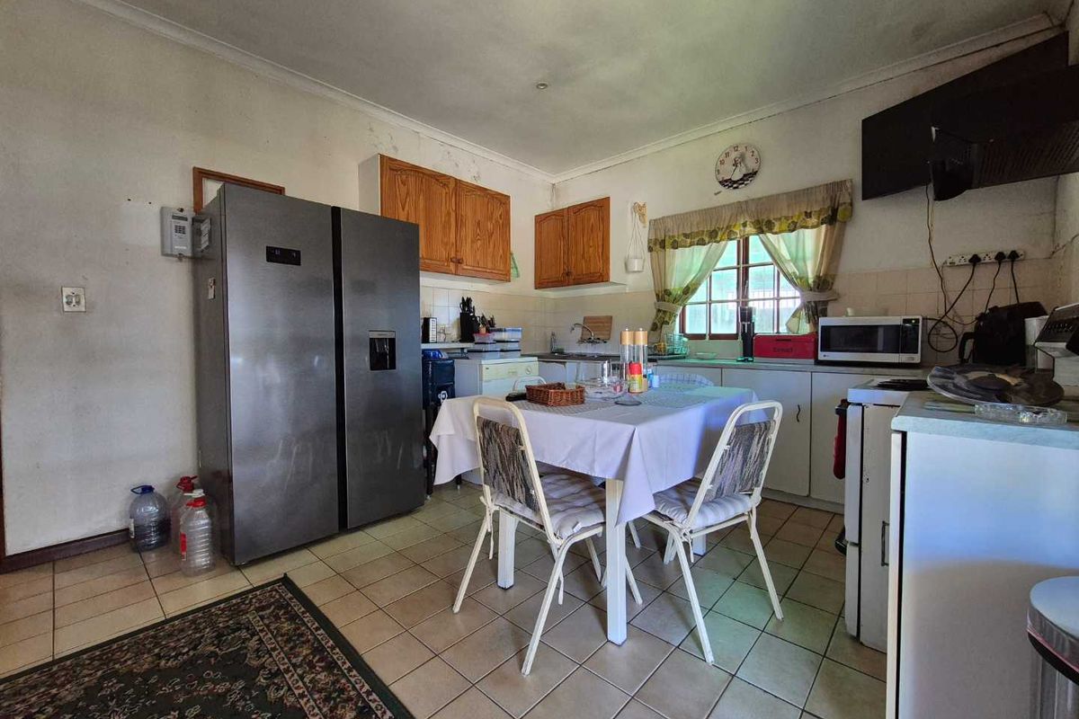 A functional kitchen featuring tiled flooring, wooden cabinetry, and a tiled backsplash, currently showing signs of wear and needing cosmetic updates.