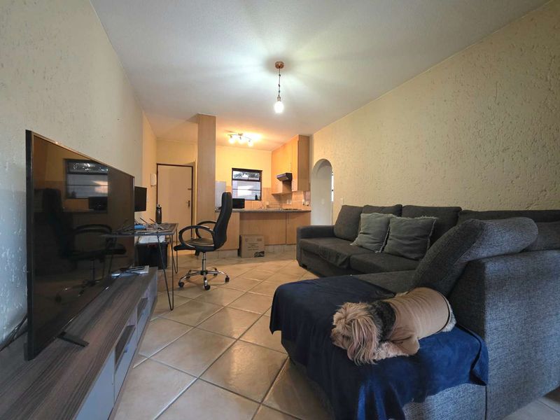 Open-plan living area featuring tiled flooring and a functional kitchen with built-in cabinetry, connected by a classic archway.