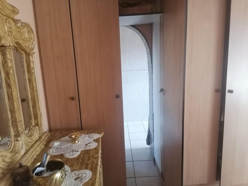 Bedroom featuring built-in wooden cupboards and an arched doorway leading to an adjacent tiled space.