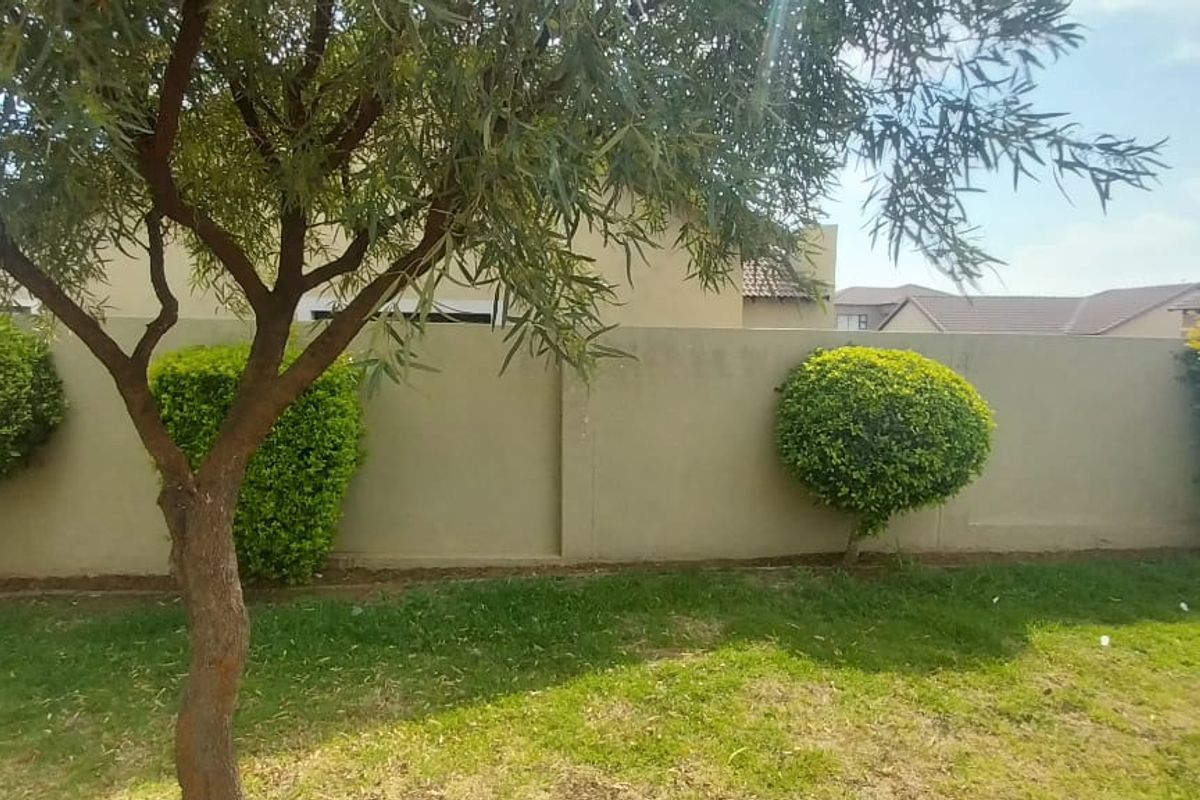 A view of the property's rear boundary wall and garden area, featuring established landscaping and perimeter walling.