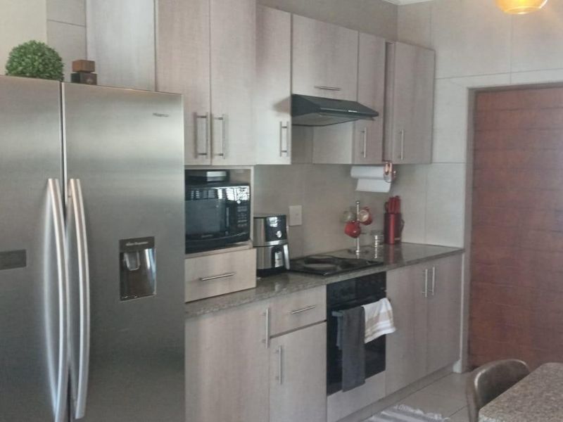 A functional kitchen featuring light wood-finish cabinetry, granite countertops, integrated appliances, and a tiled splashback, providing a clean and practical cooking space.