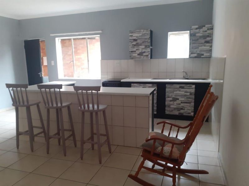 Open plan kitchen area featuring a tiled breakfast bar, built-in cabinetry, and tiled flooring in a functional cottage layout.