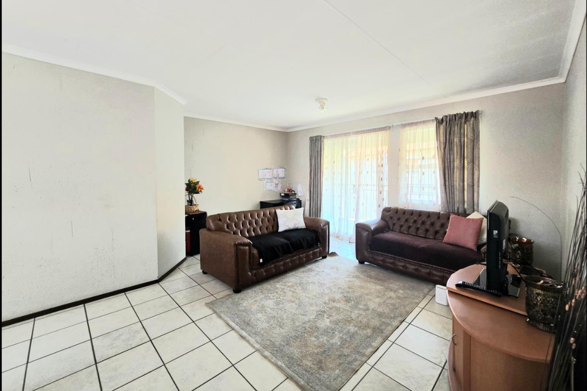 A spacious living room featuring tiled flooring and large sliding glass doors that provide natural light and access to the outdoor area.