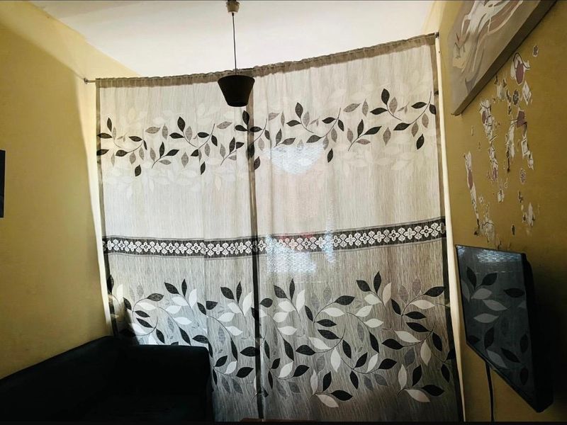 A living room area featuring a curtain-covered window and a central pendant light fixture.