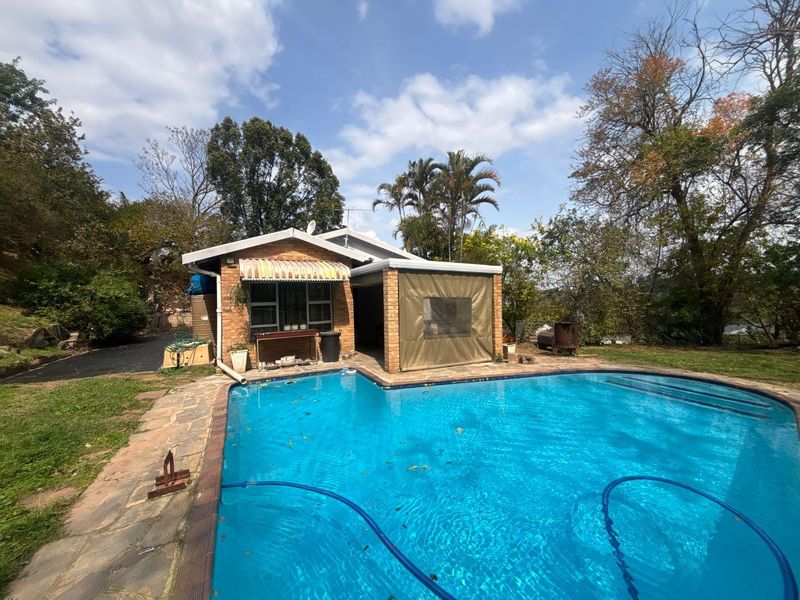Outdoor pool area featuring a brick-built dwelling with a covered patio, canvas blinds, and stone paving surrounding the swimming pool.