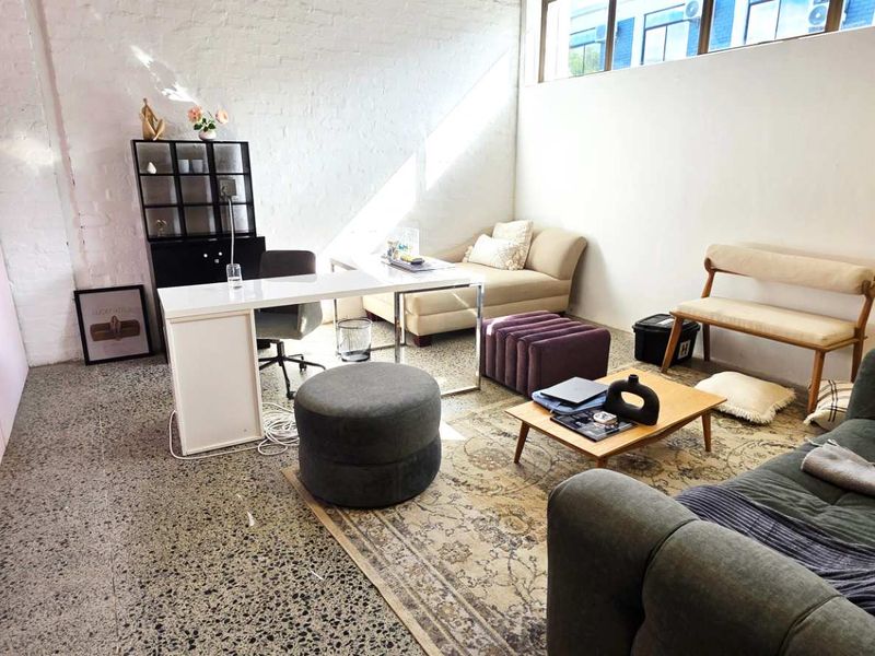 An open-plan industrial space featuring polished concrete floors, exposed brick walls, and high-level clerestory windows providing natural light.