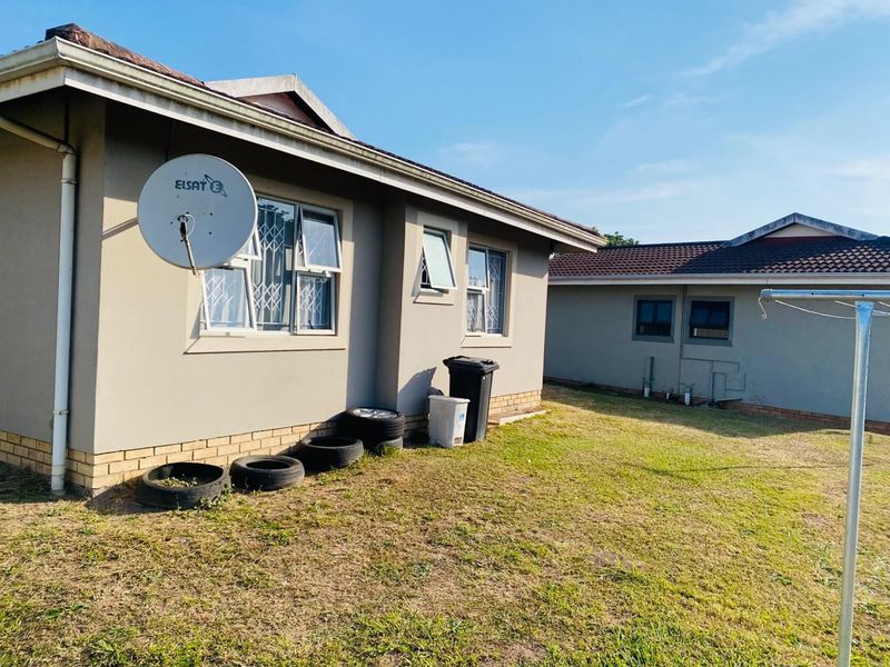 Rear exterior view of the townhouse featuring a satellite dish, security bars on windows, and a private lawn area.