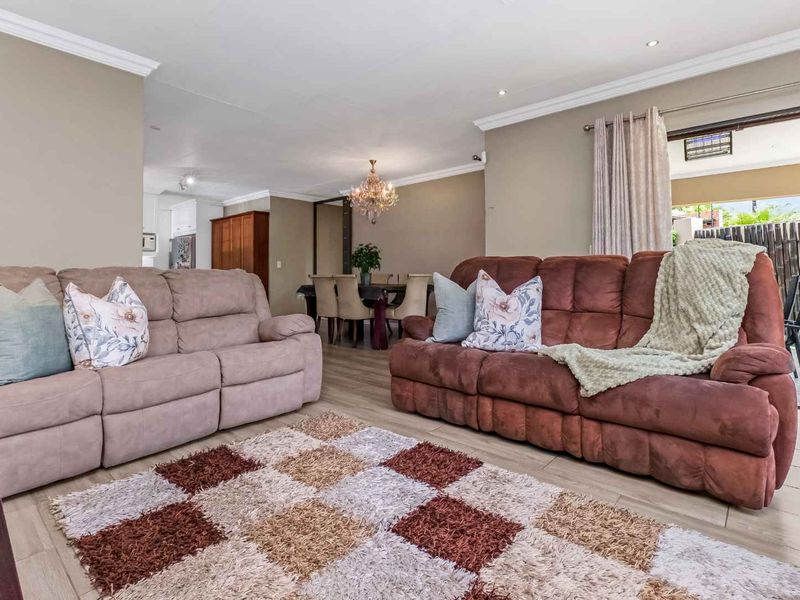 Spacious open-plan living and dining area featuring neutral wall tones, tiled flooring, recessed lighting, and direct access to an outdoor patio space.