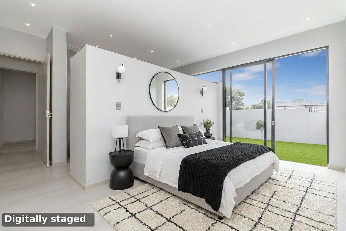 Modern bedroom featuring a partial room divider, recessed ceiling lighting, and large sliding glass doors providing direct access to the rear garden.