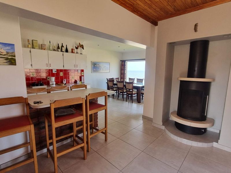 Open-plan living and kitchen area featuring a central breakfast bar, a modern freestanding fireplace, and tiled flooring with views toward the dining space.
