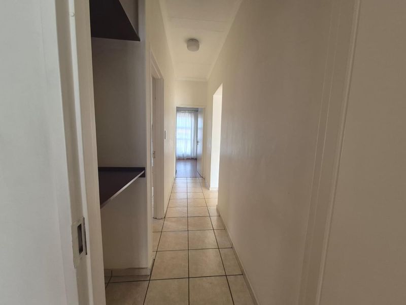 A functional hallway featuring tiled flooring and built-in shelving, providing access to other areas of the apartment.