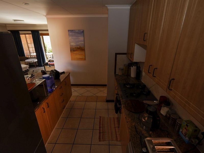 A functional kitchen featuring laminate cabinetry, granite countertops, and a gas hob, with an open-plan layout leading into the adjacent living area.