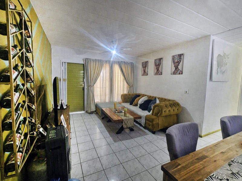 Open-plan living and dining area featuring tiled flooring, a ceiling fan, and a decorative wall-mounted wine rack, providing a functional and connected living space.