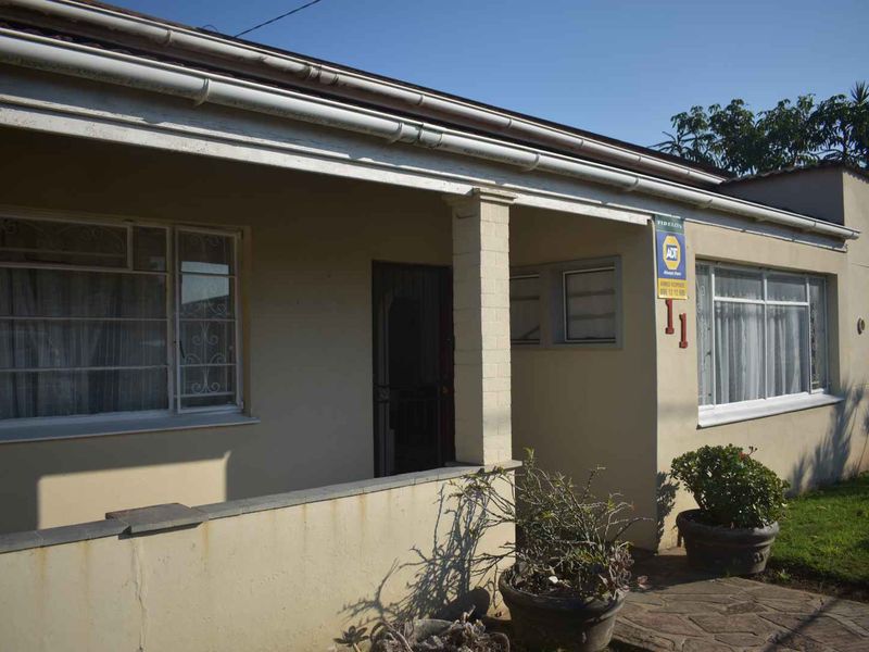 Front elevation of the house featuring a covered porch, security gate, and steel-framed windows with security bars.