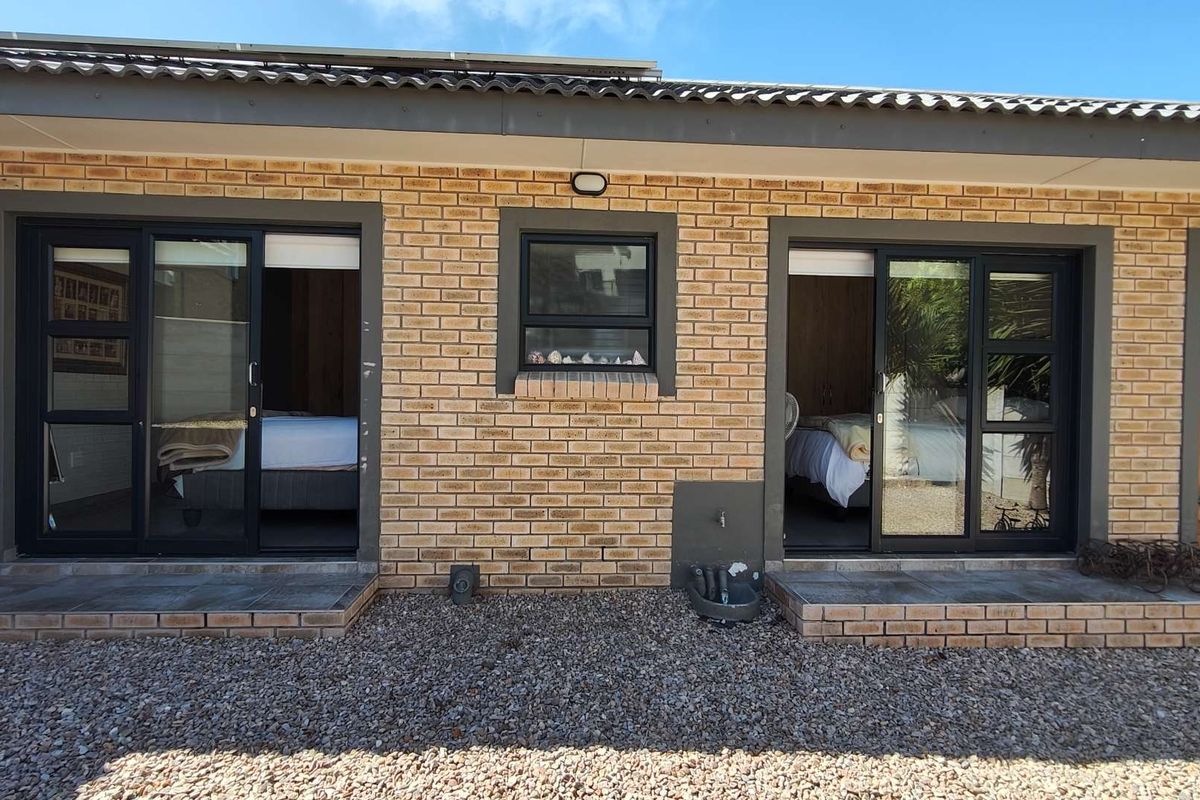 Rear exterior view of the property featuring face brick walls, sliding glass doors providing access to interior rooms, and tiled patio steps.