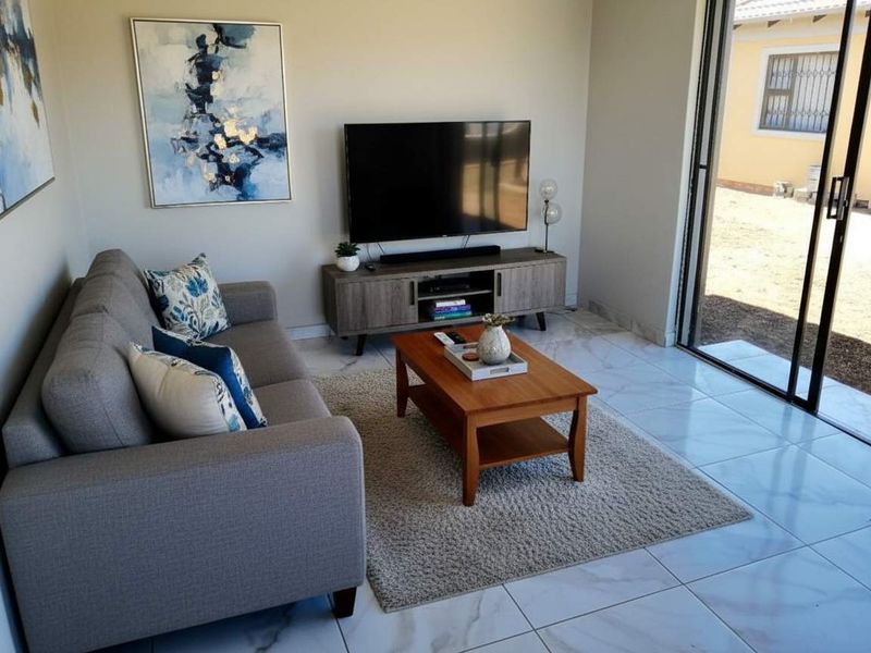 A bright living room featuring modern porcelain floor tiles and large sliding glass doors that provide direct access to the outdoor area.