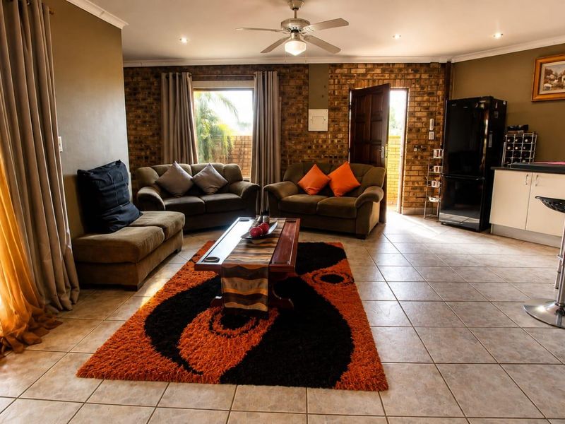 Spacious open-plan living area featuring exposed brick accents, tiled flooring, and a functional kitchen space with integrated laundry facilities.
