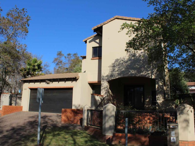 Front elevation of a two-story apartment featuring a double garage, tiled roof, and brick boundary wall with gated access.