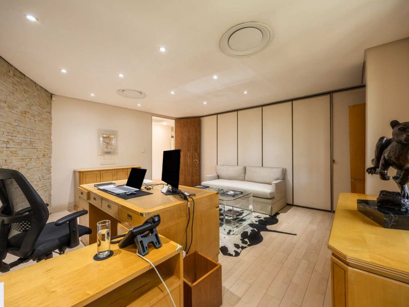 A well-appointed office space featuring a stone accent wall, recessed lighting, and extensive built-in cabinetry, providing a professional and functional work environment.