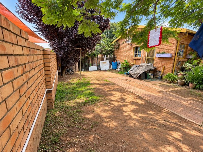 Rear garden area featuring a brick boundary wall, paved walkway, and face brick exterior wall of the house.