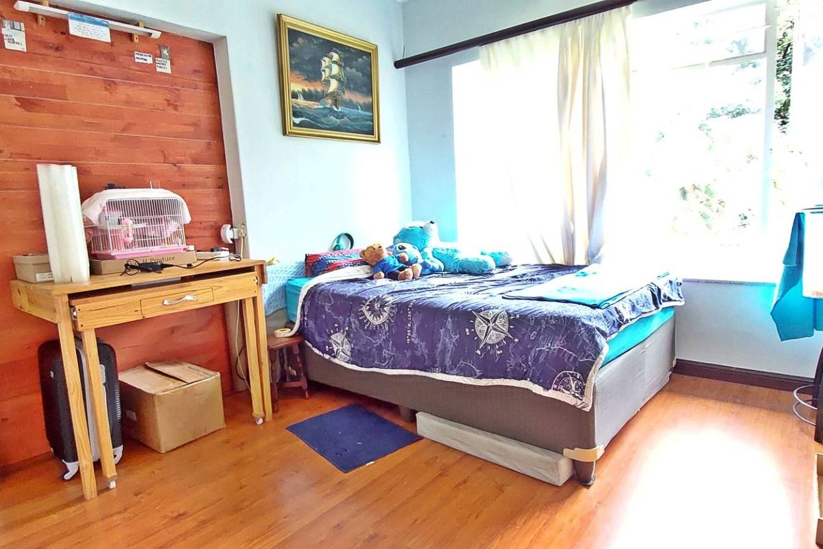A bedroom featuring timber wall paneling, laminate flooring, and a large window allowing natural light.