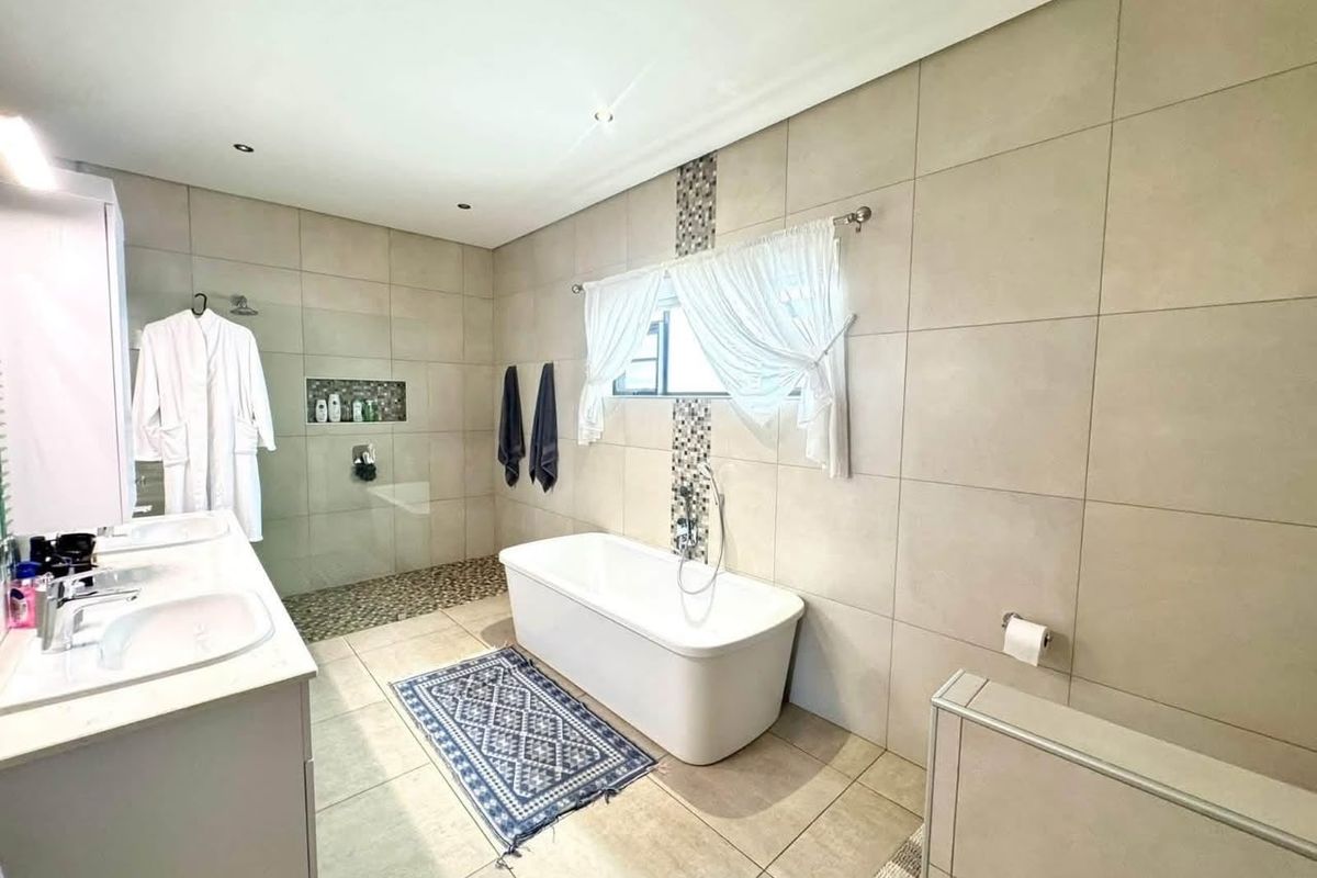 Modern bathroom featuring a freestanding bathtub, spacious walk-in shower with mosaic accents, and a double vanity with contemporary fixtures.