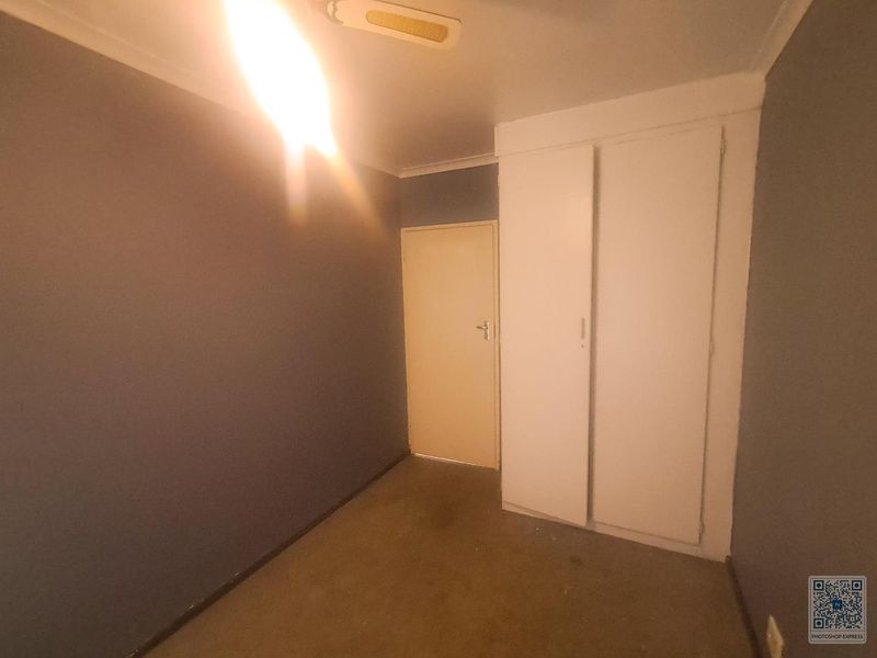 An empty bedroom featuring dark painted walls, a built-in wardrobe, and a standard ceiling light fixture.