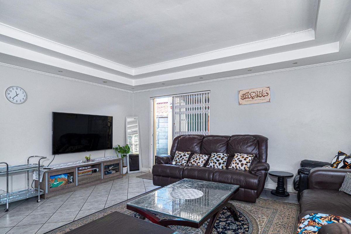 A spacious living room featuring tiled flooring, a recessed ceiling with downlights, and a sliding glass door providing access to the exterior.